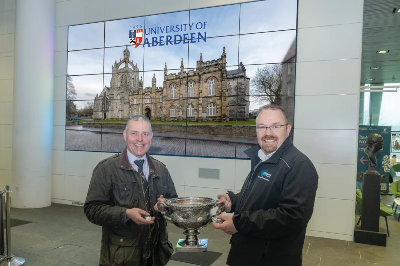Proterra Energy Operations Director Terry Stebbings and Steven MacKenzie support university shinty with new medals.